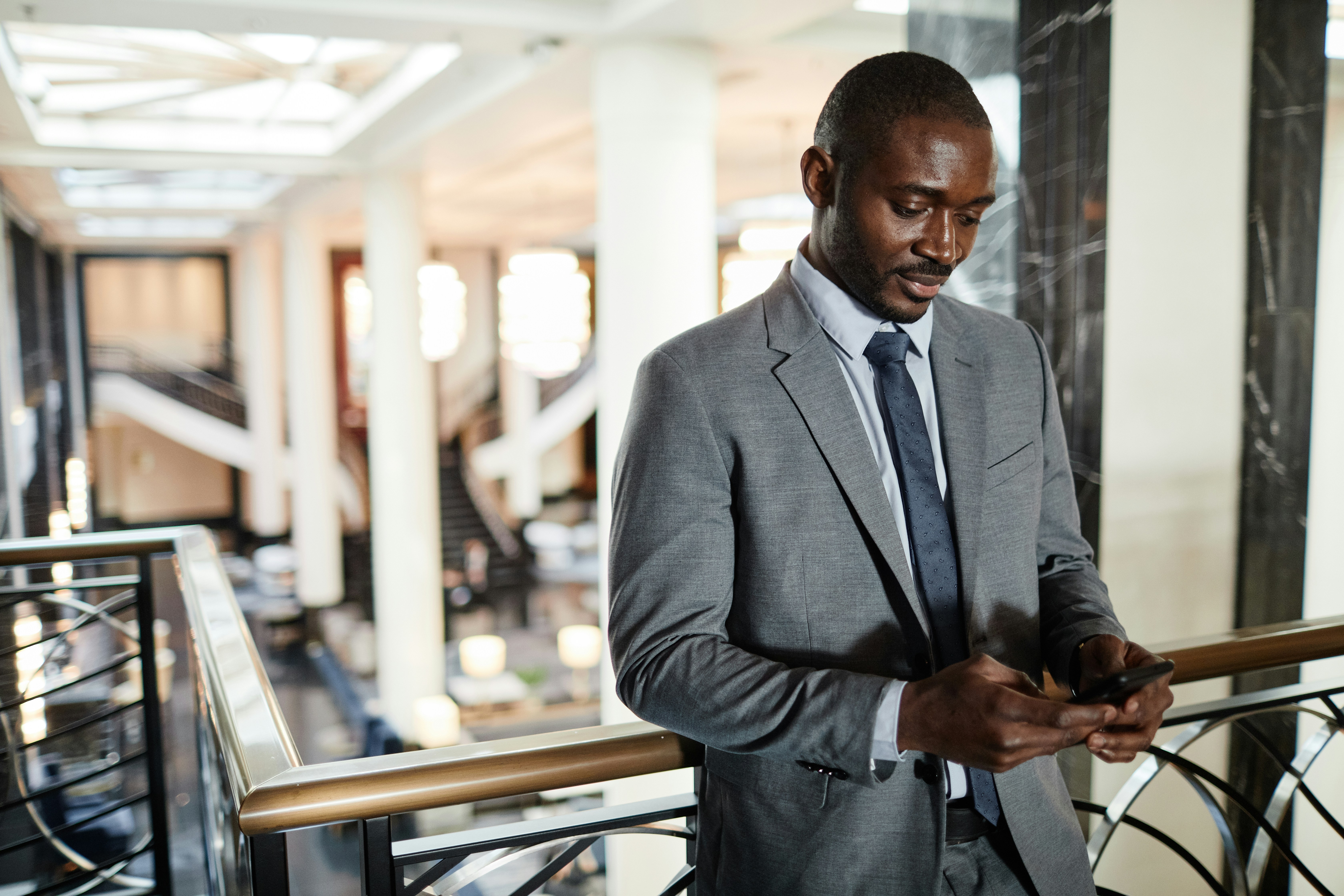 A man working for a family office service provider stands emailing from his smartphone.